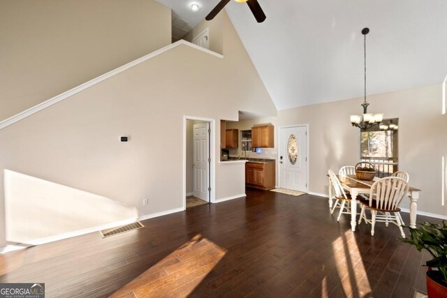 dining room with ceiling fan with notable chandelier, high vaulted ceiling, and dark wood-type flooring