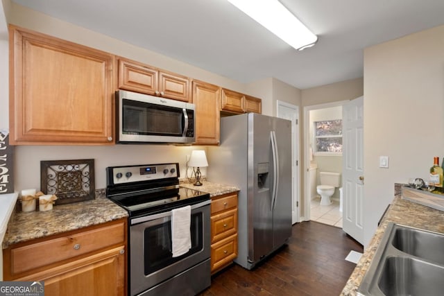 kitchen with sink, stainless steel appliances, light stone counters, dark hardwood / wood-style flooring, and light brown cabinetry