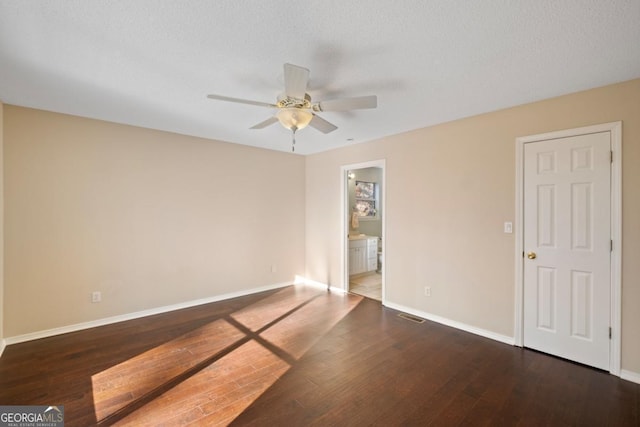 empty room featuring ceiling fan, dark wood-type flooring, and a textured ceiling