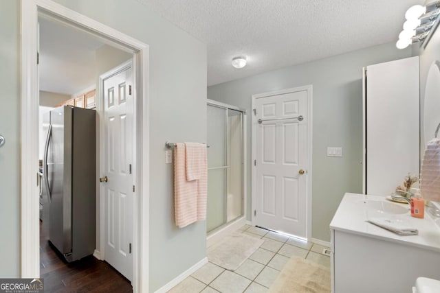 bathroom with tile patterned floors, a textured ceiling, vanity, and an enclosed shower