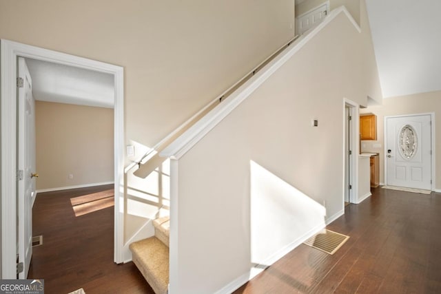 stairs featuring hardwood / wood-style floors and high vaulted ceiling