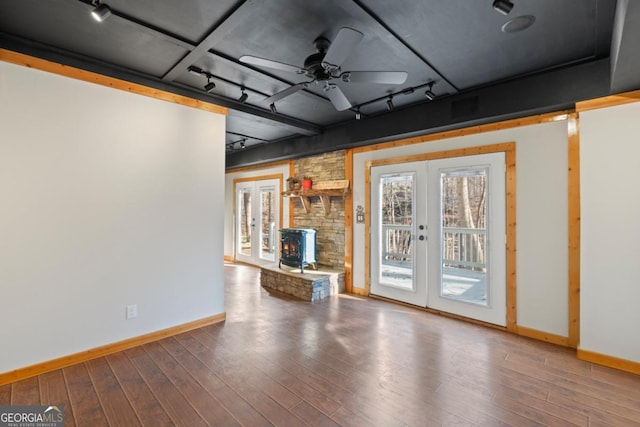 unfurnished living room with french doors, track lighting, ceiling fan, wood-type flooring, and a wood stove