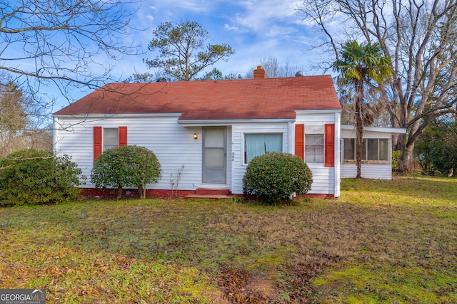 view of front of house featuring a sunroom and a front yard