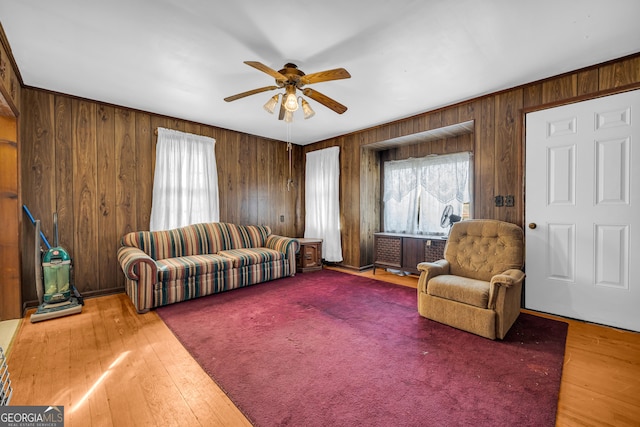 living room with wood-type flooring, ceiling fan, and wooden walls