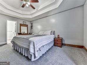 bedroom with carpet floors, a raised ceiling, and ceiling fan