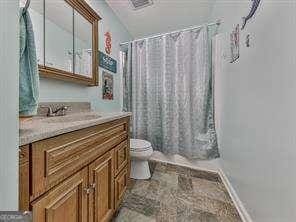 bathroom with a shower with curtain, vanity, and toilet