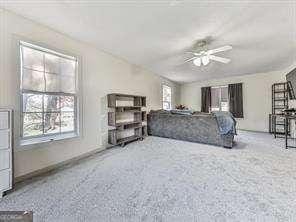 bedroom with multiple windows, ceiling fan, and carpet