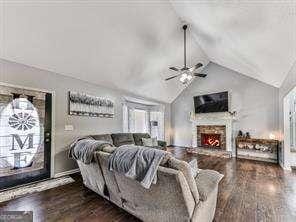 living room featuring ceiling fan, dark wood-type flooring, and vaulted ceiling