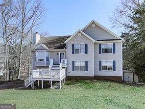 view of front facade featuring a storage unit, a wooden deck, and a front yard