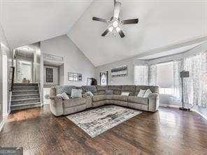 living room featuring ceiling fan, wood-type flooring, and lofted ceiling