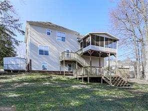 rear view of house featuring a lawn, a sunroom, and a deck