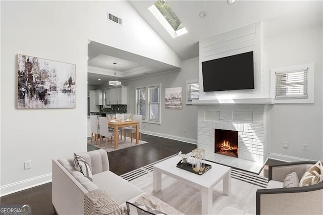 living room featuring a fireplace, wood-type flooring, vaulted ceiling, and a healthy amount of sunlight