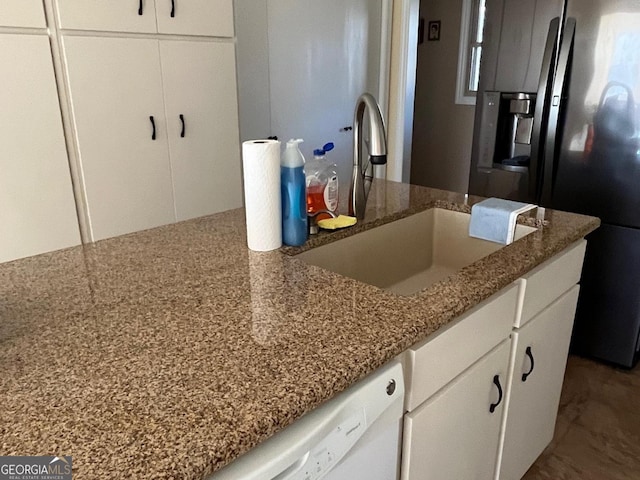 kitchen with fridge with ice dispenser, light stone countertops, white cabinetry, and sink