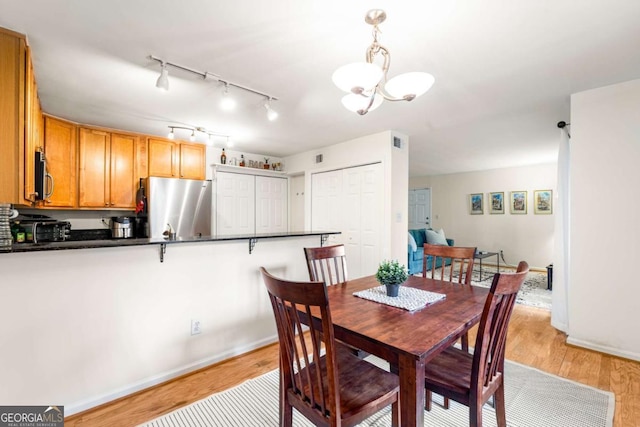 dining space with light hardwood / wood-style floors and an inviting chandelier