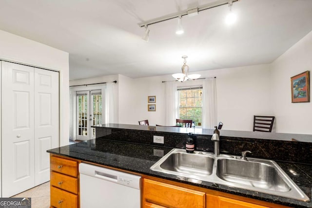 kitchen with dishwasher, track lighting, sink, light tile patterned floors, and a chandelier