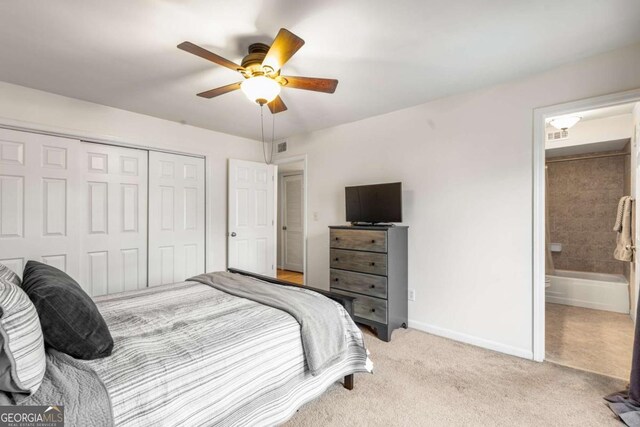 carpeted bedroom featuring ceiling fan, ensuite bathroom, and a closet