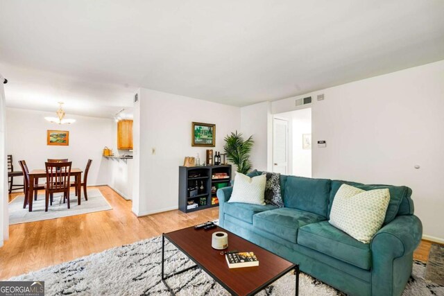 living room featuring light wood-type flooring and a chandelier