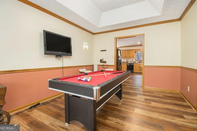 rec room featuring a raised ceiling, ornamental molding, and dark wood-type flooring