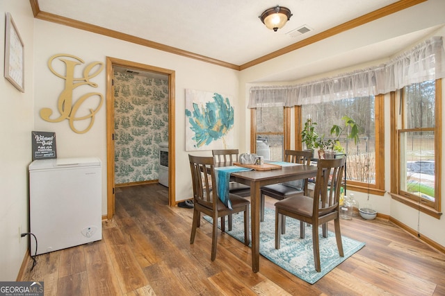 dining area with dark wood-type flooring, a healthy amount of sunlight, and crown molding