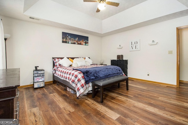 bedroom with dark hardwood / wood-style floors, a raised ceiling, and ceiling fan