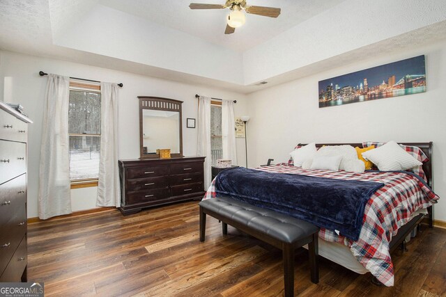 bedroom featuring connected bathroom, baseboards, a tray ceiling, and light wood-type flooring