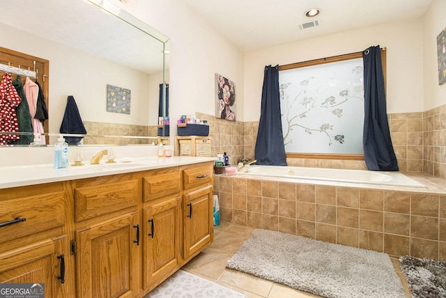 bathroom with tile patterned flooring, vanity, and a relaxing tiled tub