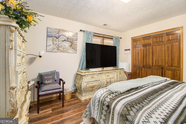 bedroom with dark wood-type flooring, a closet, and a textured ceiling