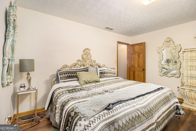 bedroom with a textured ceiling and dark hardwood / wood-style flooring