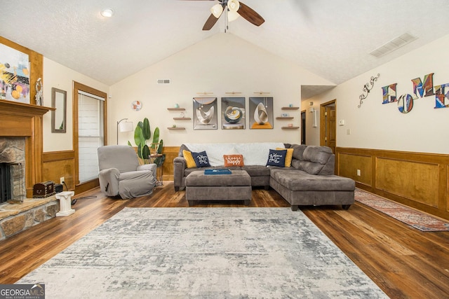 living room with a fireplace, lofted ceiling, ceiling fan, dark wood-type flooring, and a textured ceiling