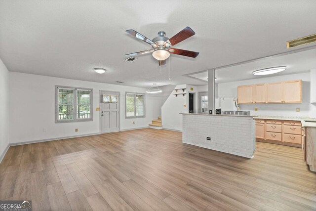 unfurnished living room featuring ceiling fan, light hardwood / wood-style floors, and a textured ceiling