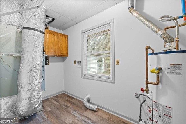 washroom featuring cabinets, hardwood / wood-style floors, and water heater