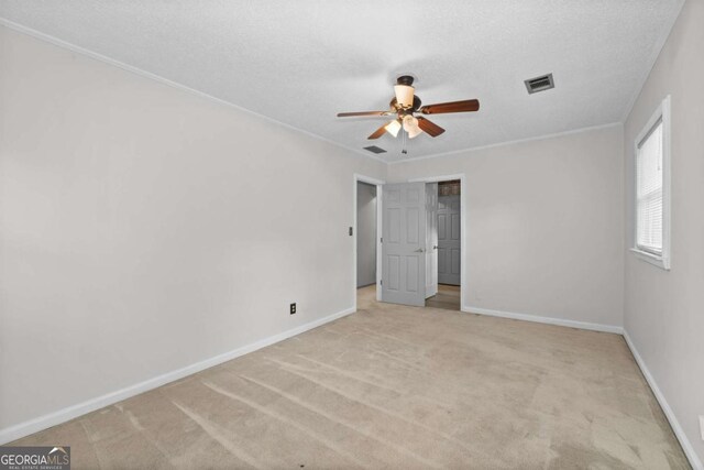 carpeted spare room featuring ceiling fan, a textured ceiling, and ornamental molding