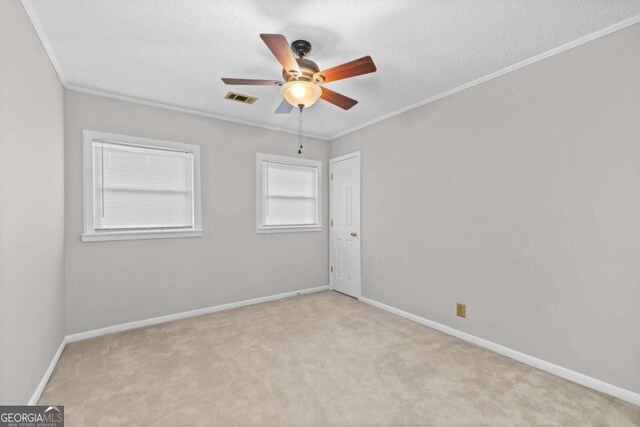 spare room with ceiling fan, light colored carpet, a textured ceiling, and ornamental molding