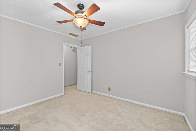 carpeted empty room with a textured ceiling, ceiling fan, and crown molding