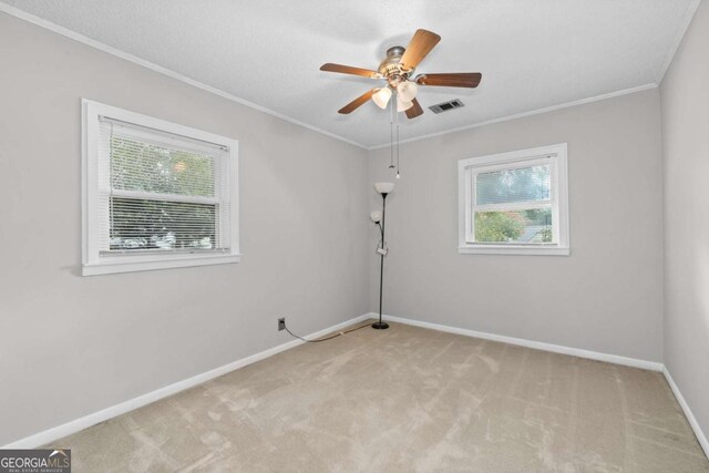 carpeted spare room featuring ceiling fan and crown molding