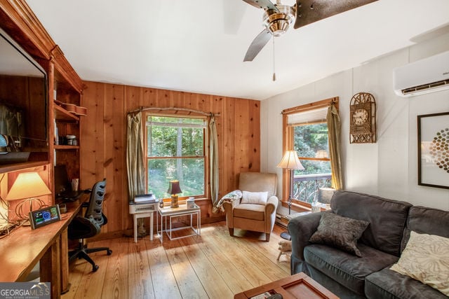 office area with wood walls, ceiling fan, light hardwood / wood-style floors, and an AC wall unit