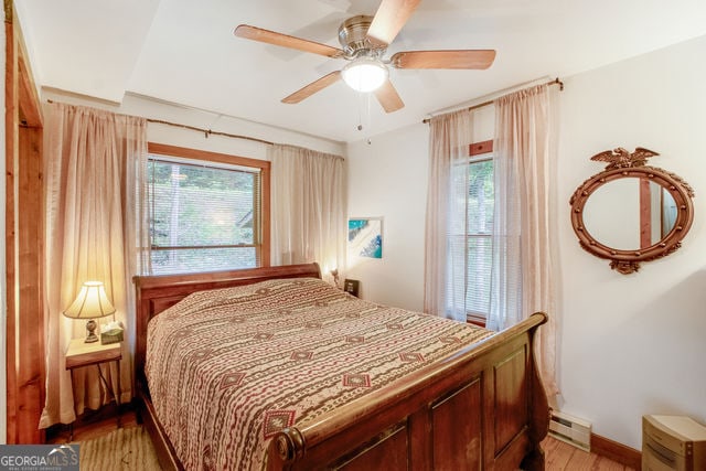 bedroom featuring ceiling fan, a baseboard radiator, and light hardwood / wood-style floors