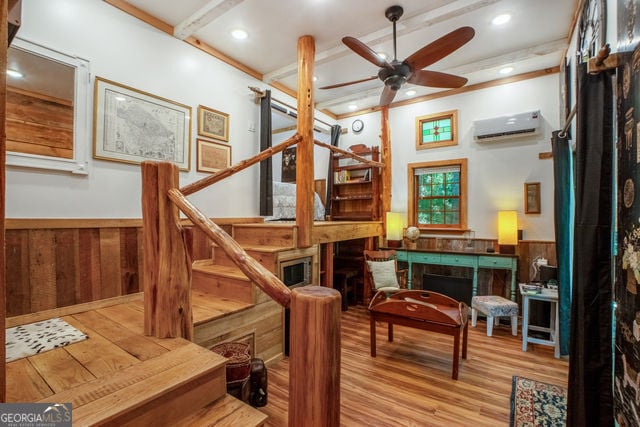 interior space with wood walls, ceiling fan, light hardwood / wood-style floors, and a wall mounted AC