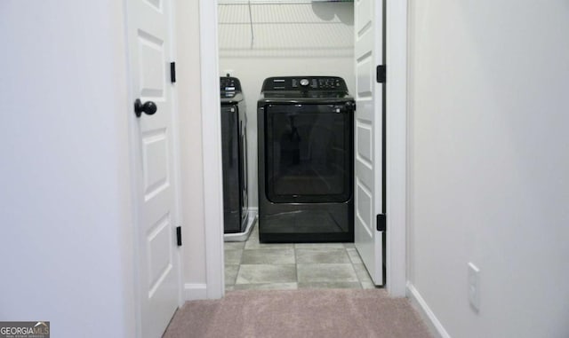 clothes washing area featuring light colored carpet and washer and dryer