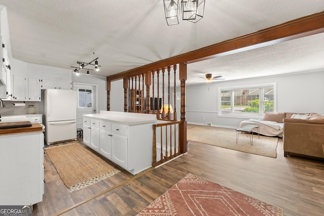 kitchen featuring white cabinets, white refrigerator, hardwood / wood-style flooring, ceiling fan, and a textured ceiling