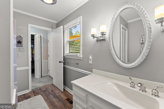 bathroom with vanity, wood-type flooring, a textured ceiling, and ornamental molding