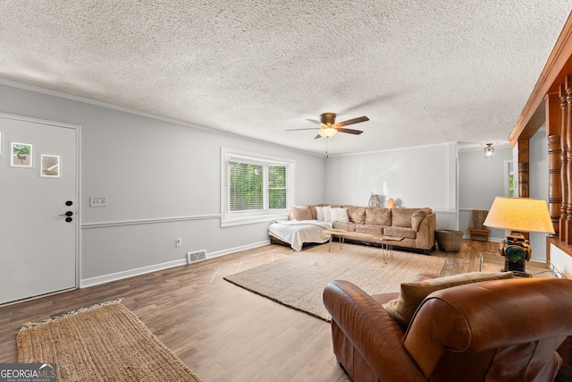 living room featuring ceiling fan, crown molding, wood-type flooring, and a textured ceiling