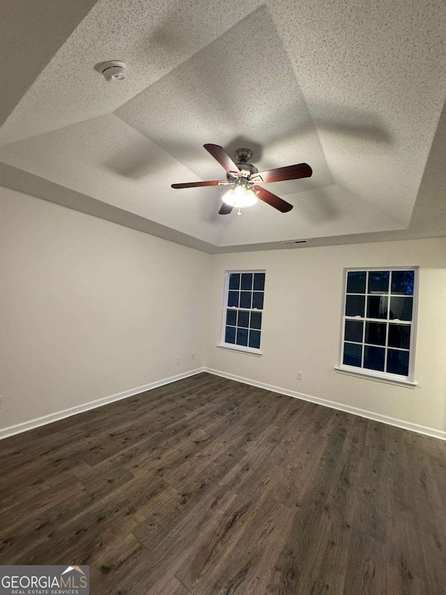 spare room featuring ceiling fan, dark wood-type flooring, and a tray ceiling