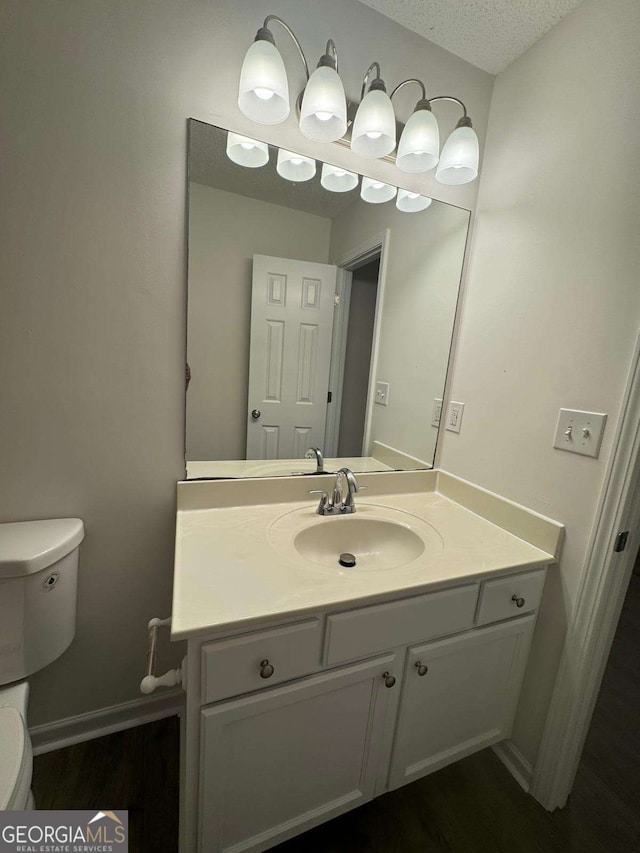 bathroom with vanity, a textured ceiling, and toilet