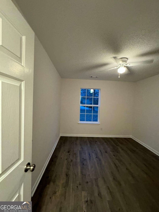 spare room with a textured ceiling and dark wood-type flooring