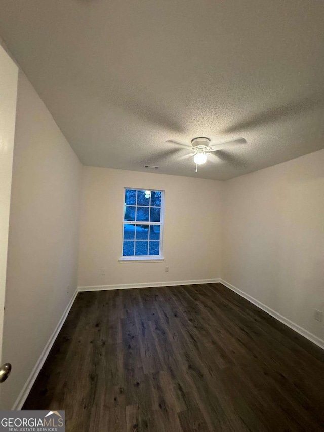 empty room with dark hardwood / wood-style flooring and a textured ceiling