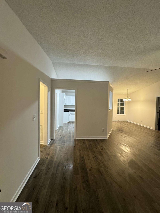 unfurnished room featuring a textured ceiling, dark hardwood / wood-style flooring, a chandelier, and lofted ceiling