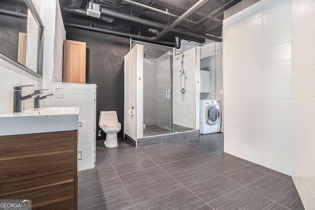 bathroom featuring vanity, tile patterned floors, toilet, walk in shower, and washer / clothes dryer