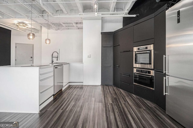 kitchen with white cabinets, sink, dark hardwood / wood-style floors, appliances with stainless steel finishes, and decorative light fixtures