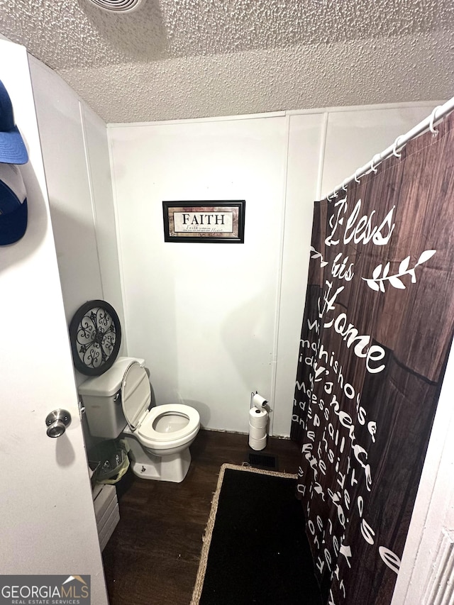 bathroom featuring toilet, wood-type flooring, and a textured ceiling